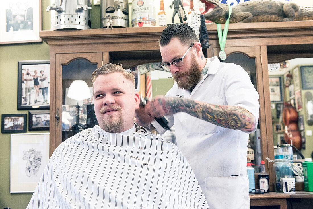 Professioneel barbier verzorgt het haar van een van zijn mannelijke klanten in de barbershop.