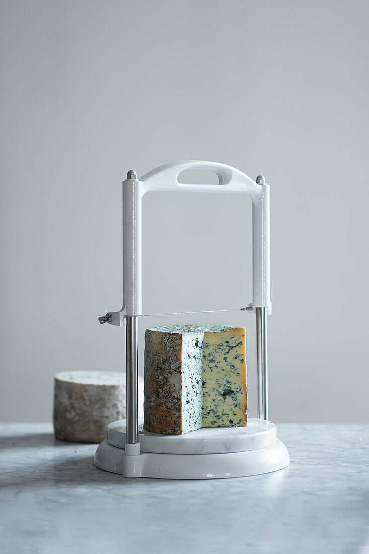 In Scheiben geschnittener Blauschimmelkäse auf einer Käse-Guillotine