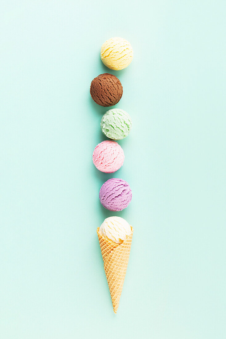 Flying scoops of ice cream in a cone on a pastel light blue background. Summery minimal concept