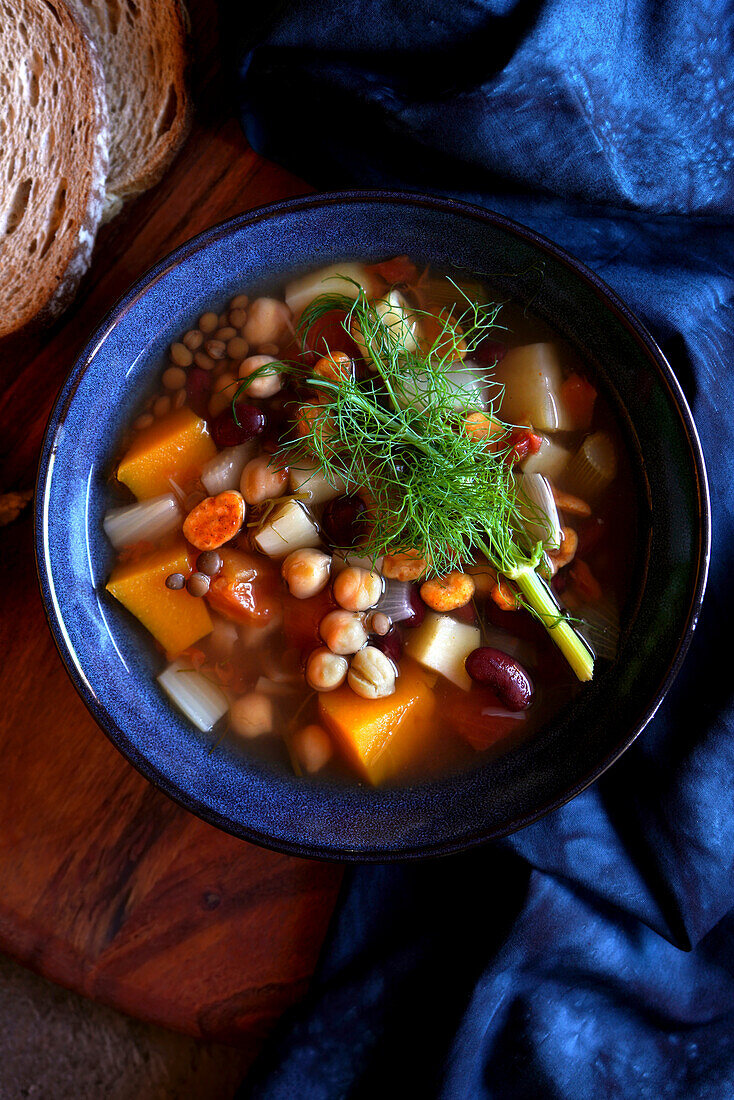 Sardinian-style minestrone longevity soup served with sourdough bread. Close up top down flatlay.