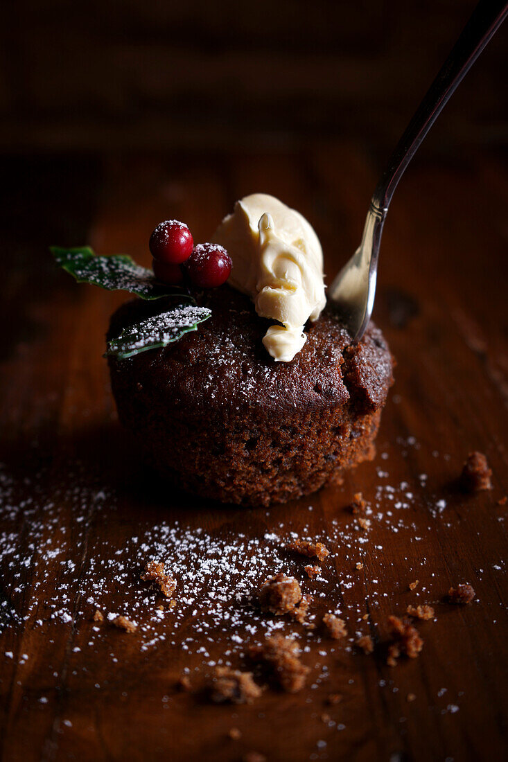 Mini Christmas plum pudding with a dollop of cream, close-up.