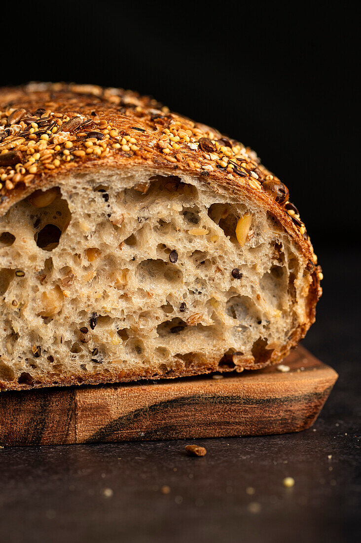 A fresh loaf of multigrain bread against a dark background