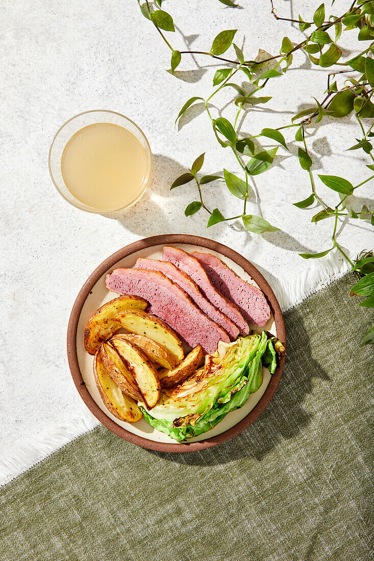 Corned Beef, Bratkartoffeln und Kohlgericht auf grünem und weißem Hintergrund