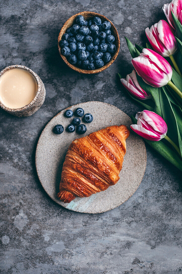 Croissant and blueberries on a ceramic plate