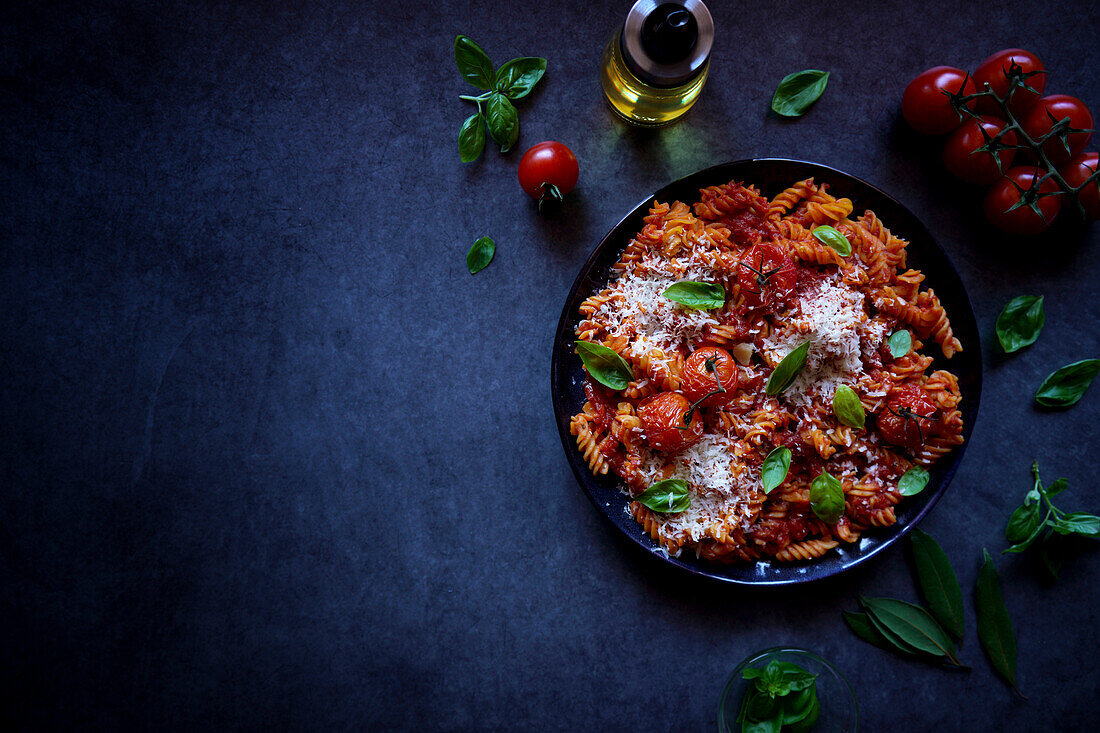 Pflanzenbasierte, proteinreiche Pasta aus roten Linsen mit gebratenen Rispentomaten und Basilikum, mit negativem Kopierraum.