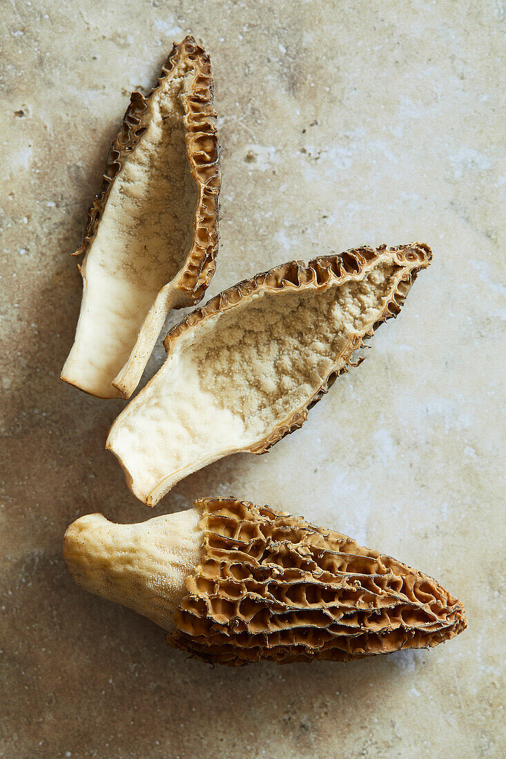 Black morels in close-up on a beige stone background