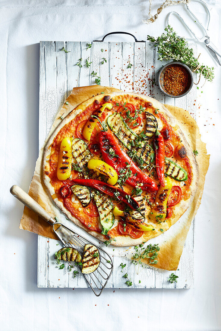 Pizza mit gegrilltem Gemüse auf einem Holzbrett