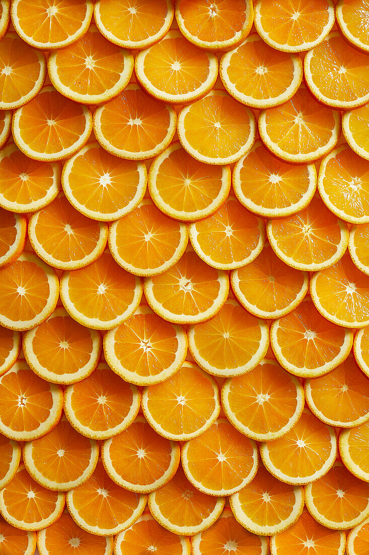 Lots of freshly cut orange slices laid out from above like scales