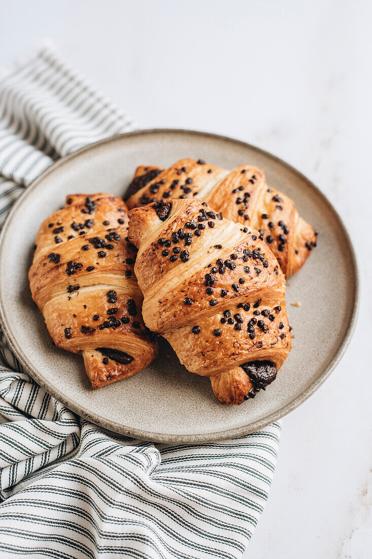 Schokoladencroissants auf Teller und weißem Hintergrund