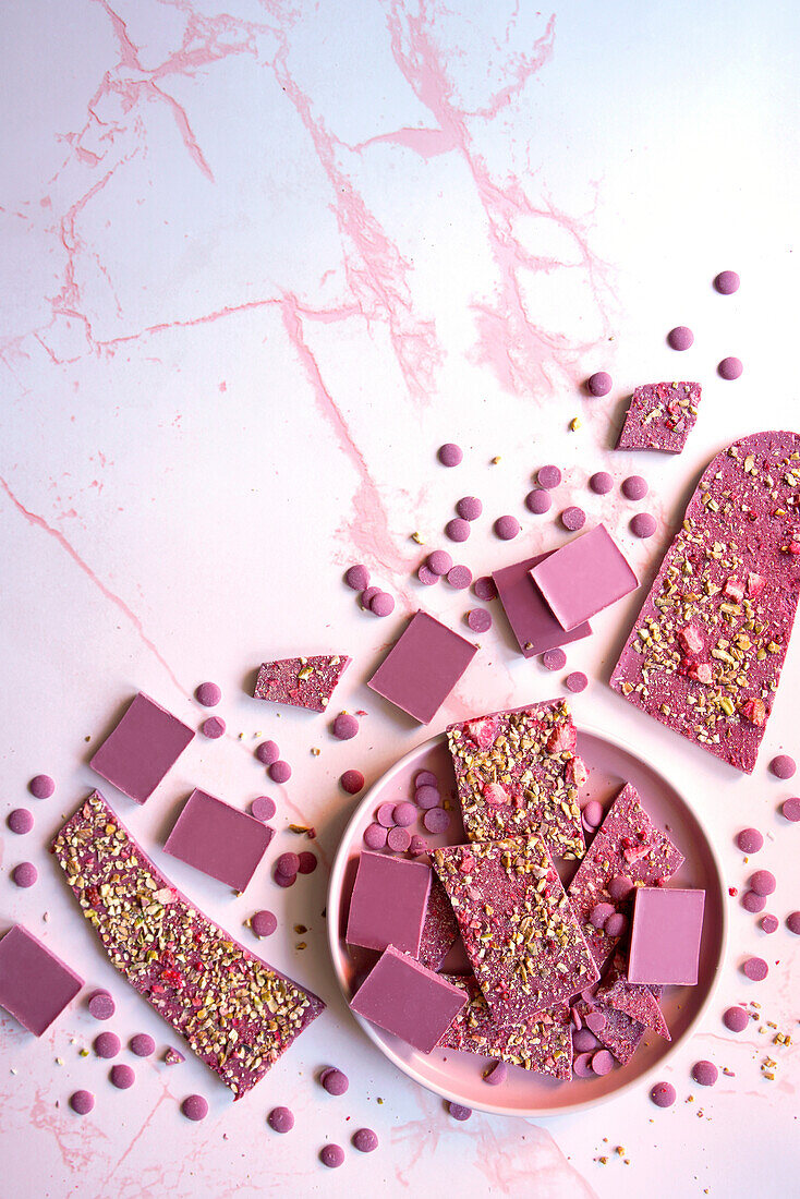 Ruby chocolate made from selected botanical cocoa bean varieties. Selection of bars, callets and dried strawberry and pistachio bark.