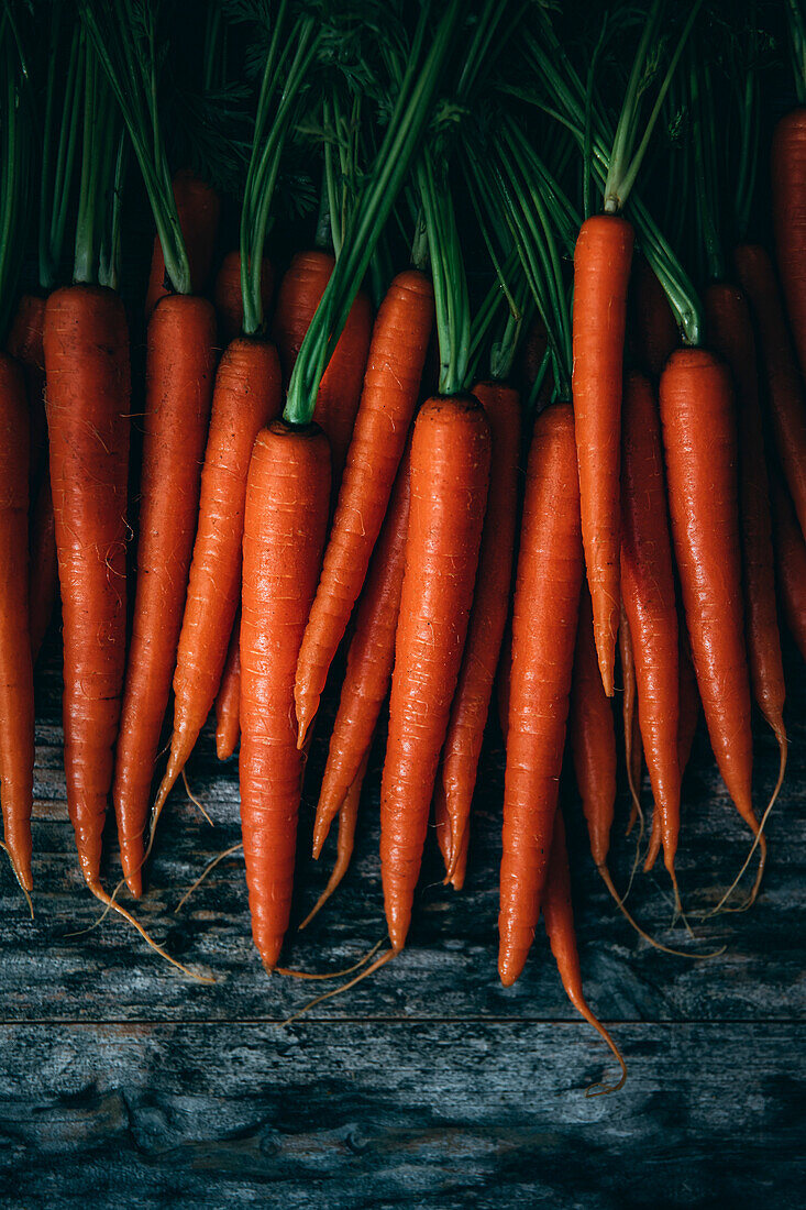 Stacked carrots against a wooden background