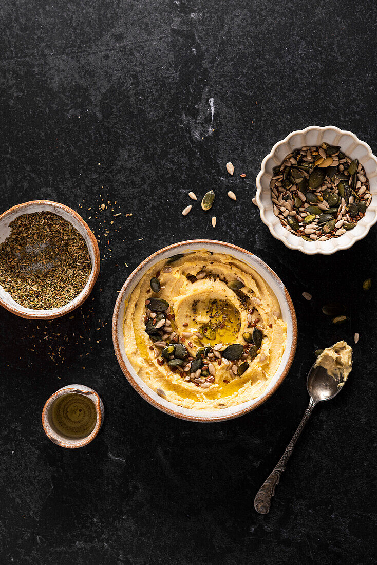 Bowl of hummus with seeds, olive oil, oregano