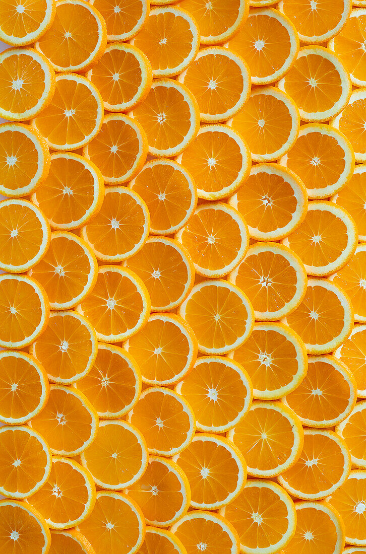 Many freshly cut orange slices laid out like scales from above