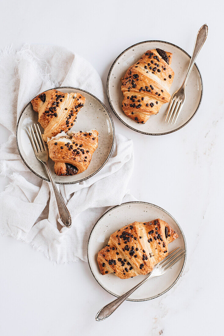 Schokoladencroissants auf Teller und weißem Hintergrund