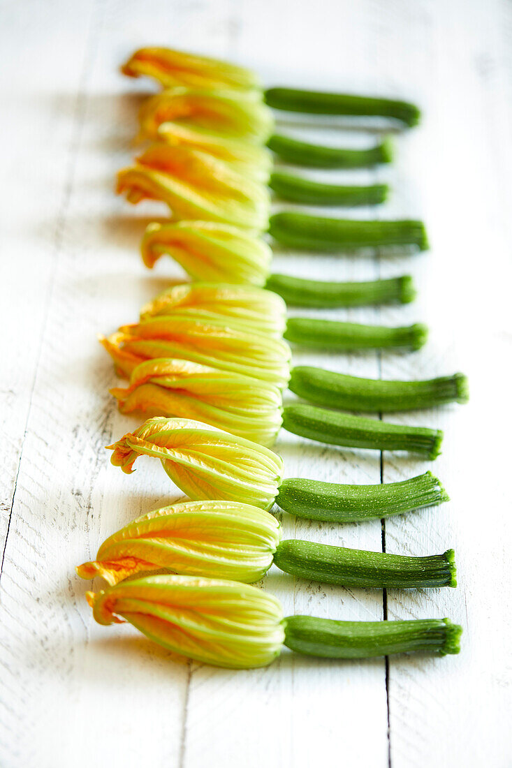 Fresh home-grown zucchini flowers on a white wooden background