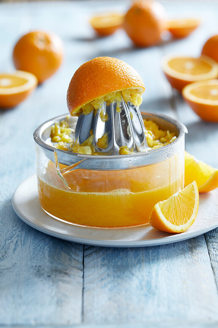 Frisch gepresster Orangensaft in einer Orangenpresse auf blauem Hintergrund