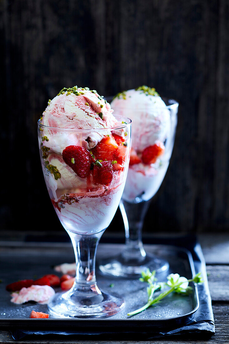 Strawberry ice cream served in a glass and decorated with strawberries