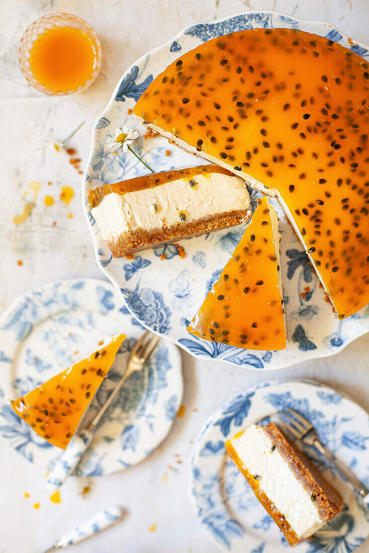 Passionfruit cheesecake slices being put onto plates. The cheesecake has a biscuit base and a passion fruit jelly on the top.