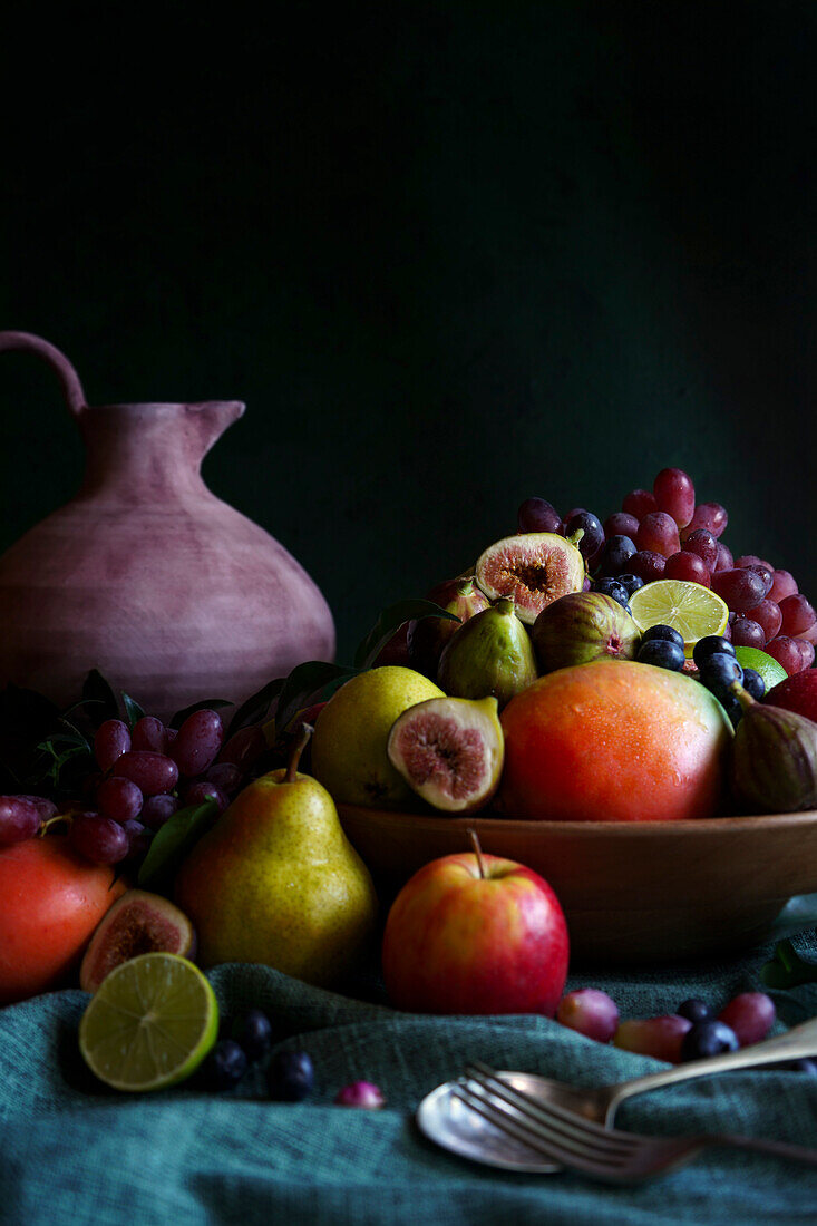 Seasonal autumn fruit bowl with apples, pears, mangoes, figs, limes and grapes. Negative copy space.