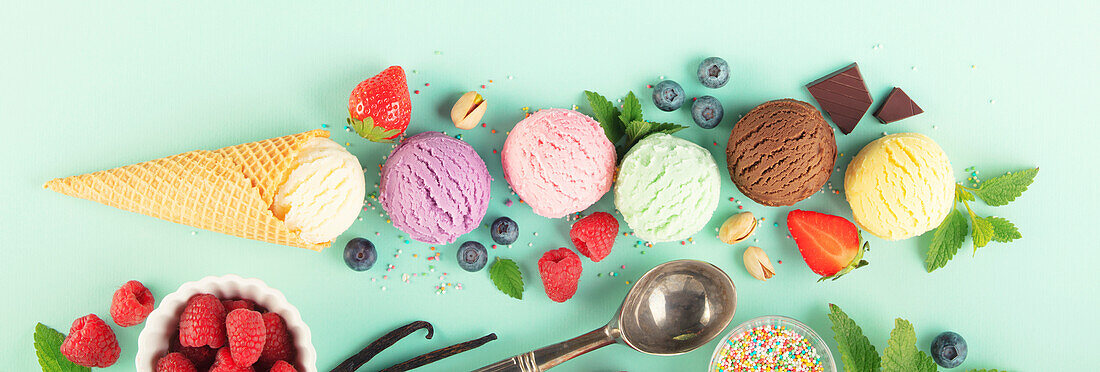 Fliegende Eiskugeln und Zutaten auf pastellfarbenem hellblauem Hintergrund. Sommerliches Minimal-Konzept