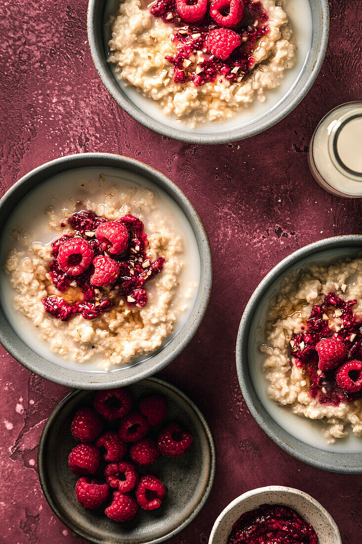 Breakfast Oatmeal porridge with raspberries on red surface