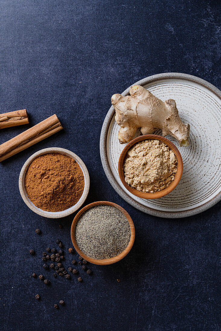 Raw ingredients with their ground spices as a flat lay on a blue background