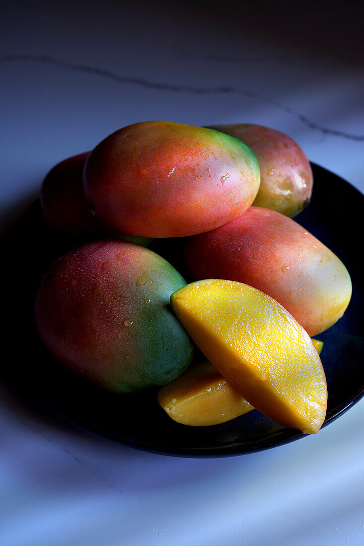 Plate of colorful mango tropical summer fruit close up.