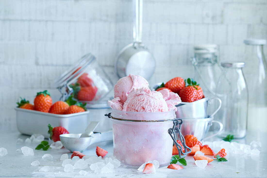 Strawberry ice cream in a preserving jar with strawberries on a light background