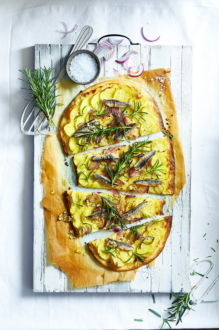 Homemade pizza with potatoes, sardines, rosemary and red onions