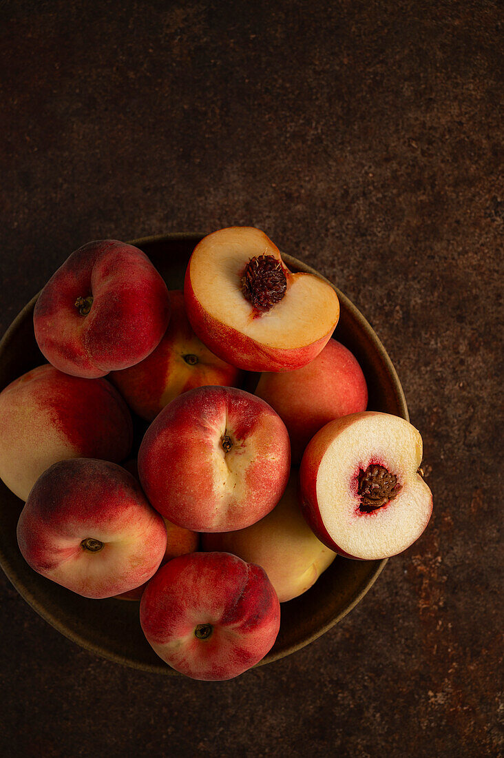 A Bowl of Peaches on Brown Backdrop