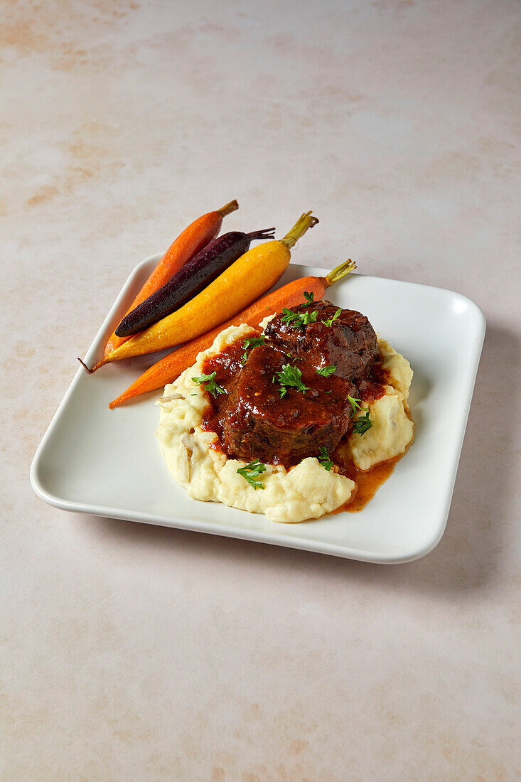 Beef Short Ribs with Mashed Potatoes and Rainbow Carrots on a Neutral Background with Soft Shadows