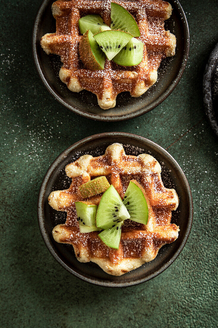 Morgenwaffeln mit Kiwi und Gabel auf einer grünen Fläche