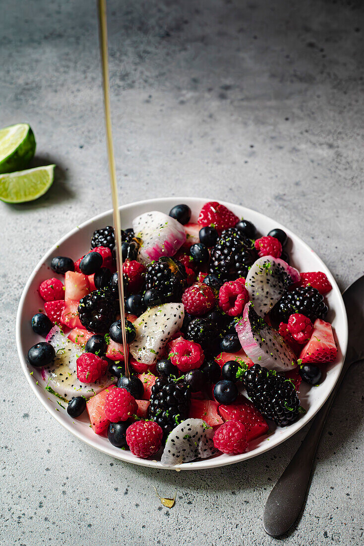 pouring honey on a berry fruit salad