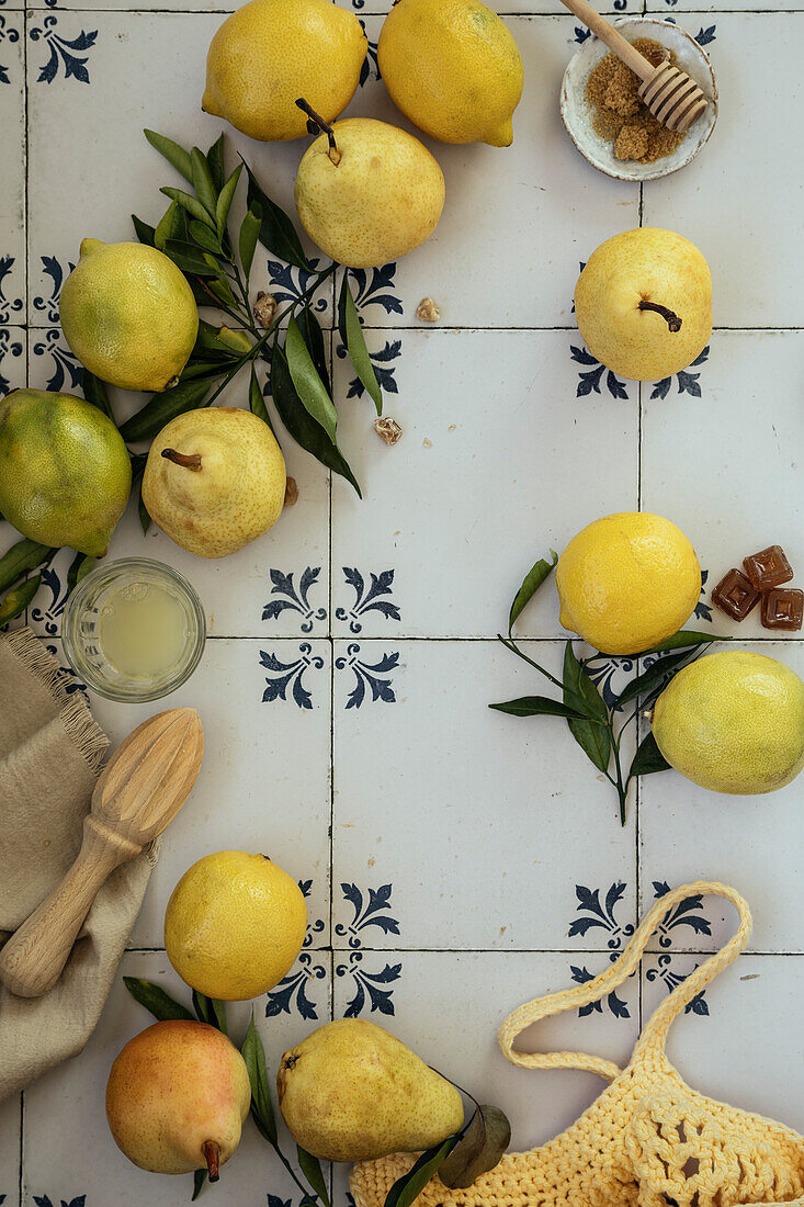 Fresh lemons and pears with leaves. Bag of yellow lemons and pears with fresh lemon tree leaves on a blue tile background. Flat lay