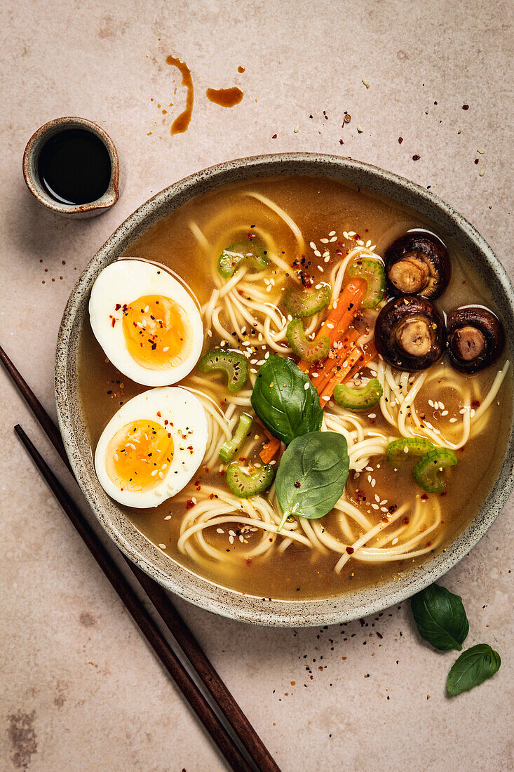 Ramen mit Nudeln, Eiern, Pilzen, Karotten und Sesam auf hellem Hintergrund