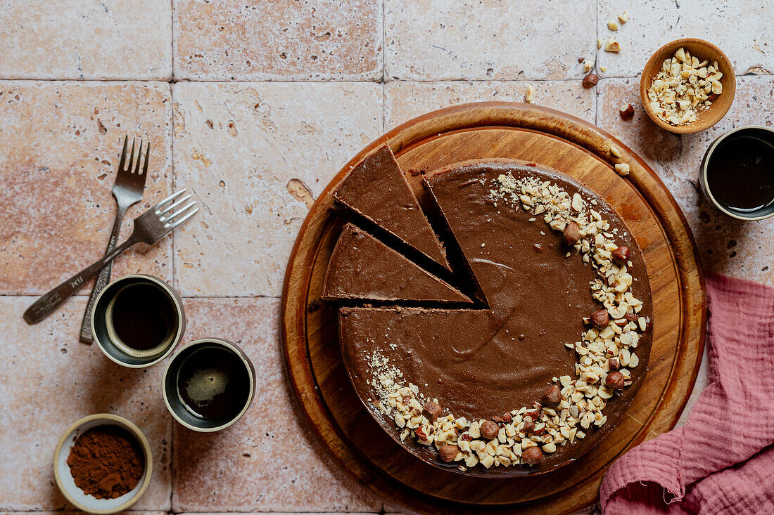 Landschaftsaufnahme von Schokoladenkäsekuchen mit Haselnüssen und Kaffee auf Fliesen