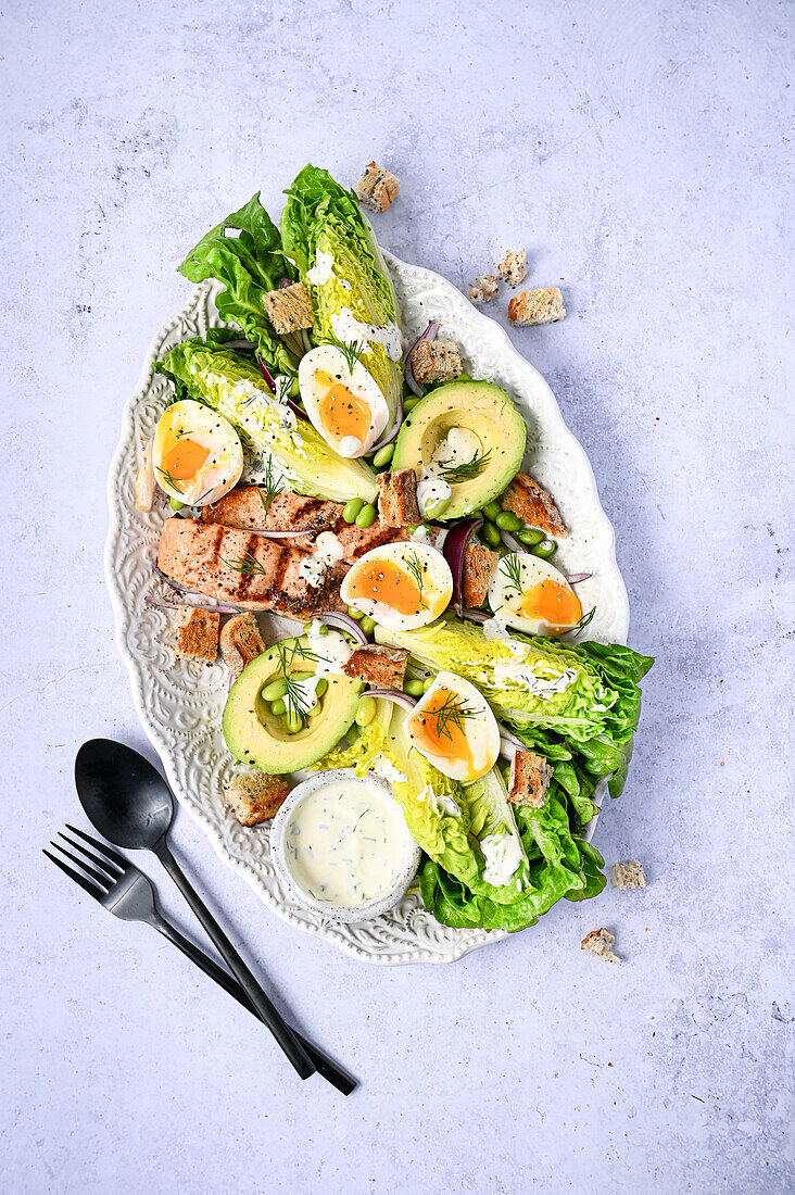 Lachs-Caesar-Salat auf hellblauem Stein