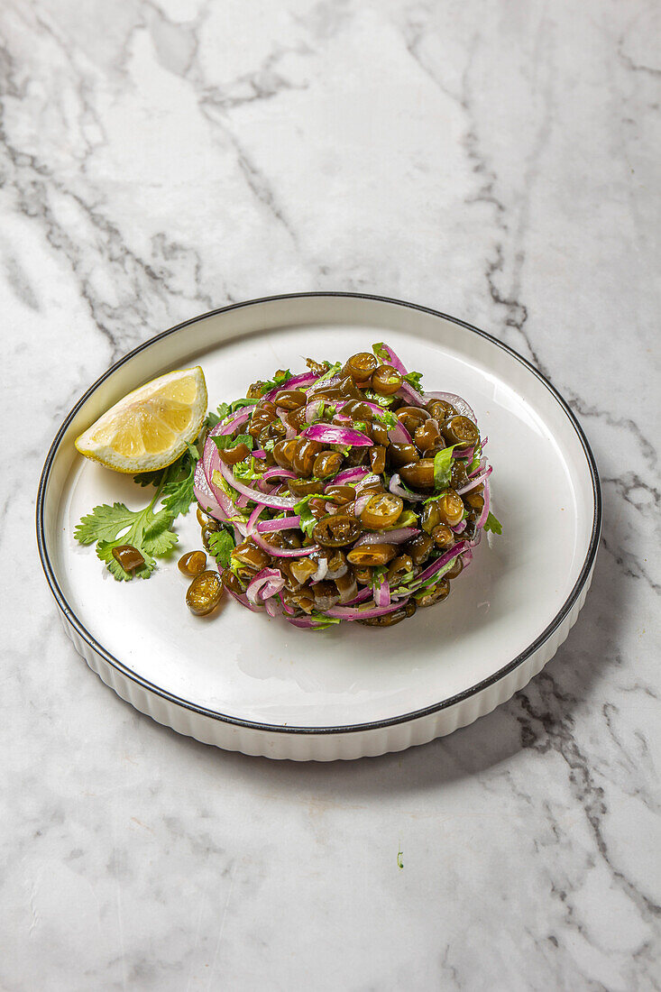 Seetang-Salat. Chilenische Cebiche de cochayuyo aus gehackten Cochayuyo-Algen mit Zitronen, Koriander, Zwiebeln und Salz, weißer Teller, Ansicht von oben