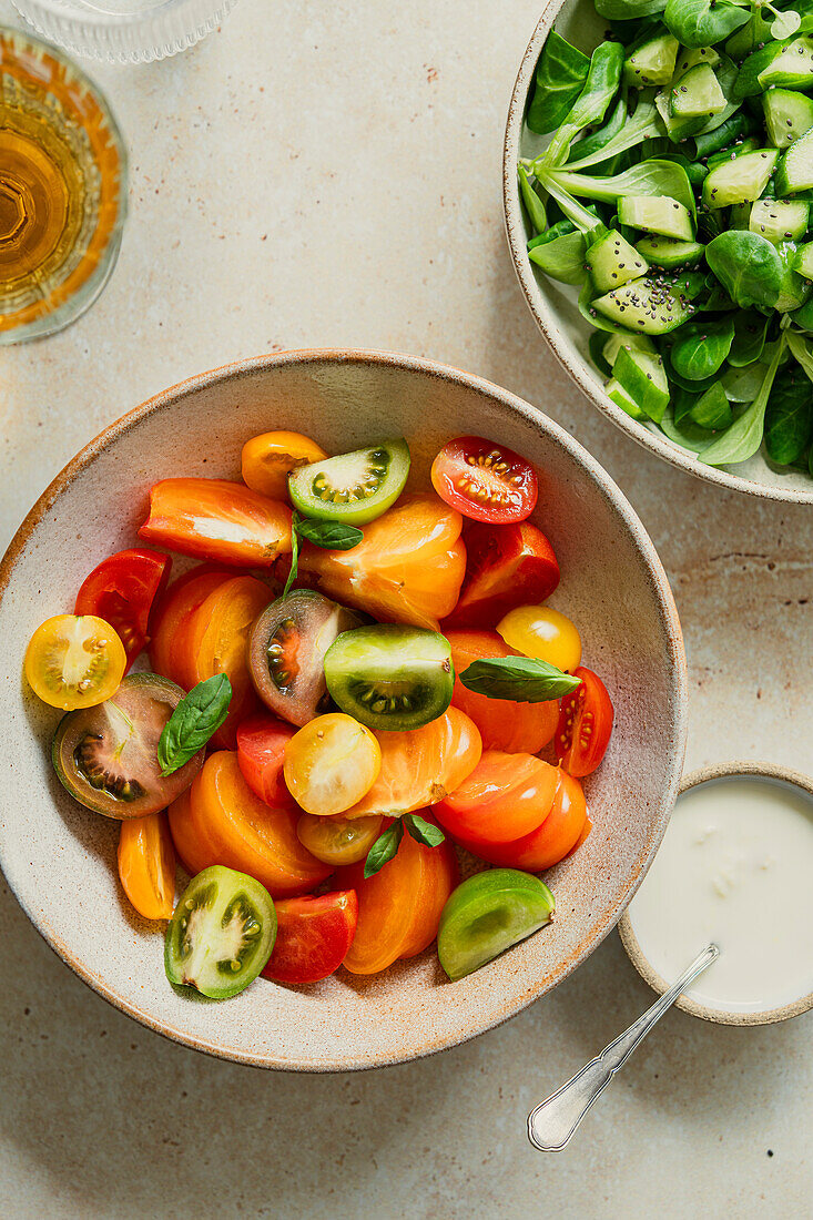 Frischer Tomatensalat in einer Schüssel mit Joghurtdressing an der Seite