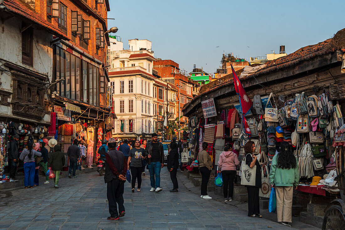 Geschäfte mit Hanf-Rucksäcken und Besucher in den Straßen um das historische Zentrum bei Sonnenuntergang, Durbar Square, Kathmandu, Nepal, Asien