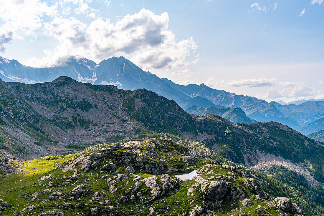 Bergwiese mit einem See auf einem Hochplateau und Blick über hohe Berge mit hoch aufragenden Gipfeln der Schweizer Alpen am Horizont, Schweiz, Europa