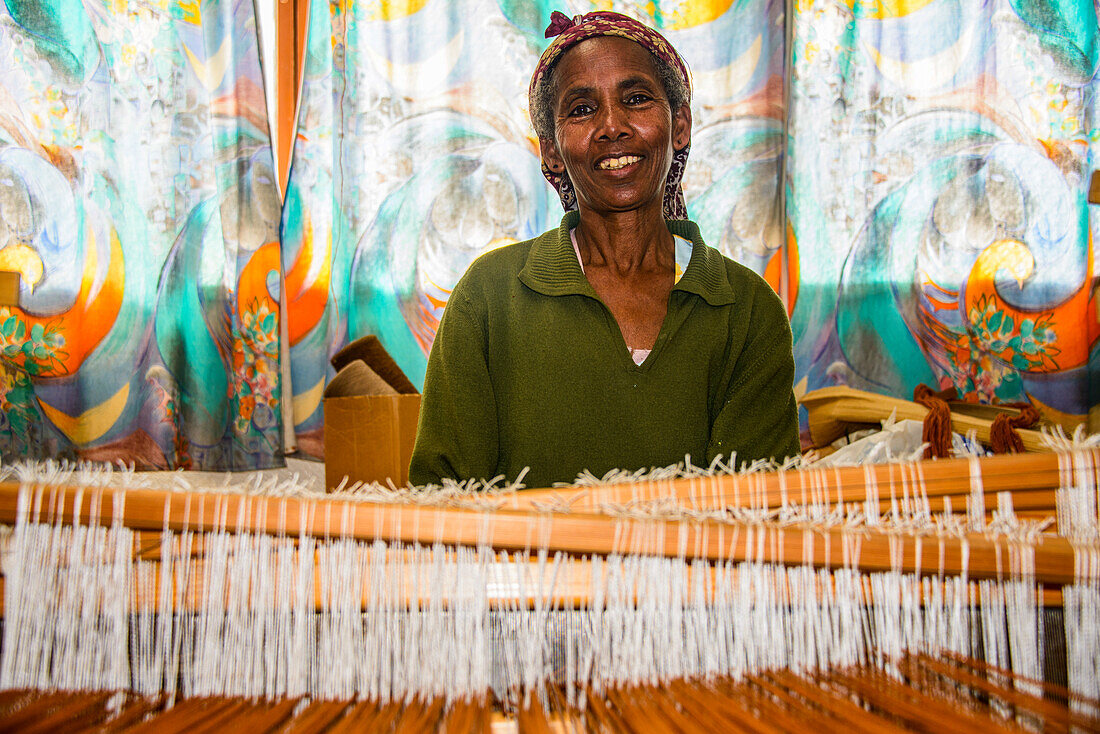 Freundliche Frau bei der Arbeit an einem Handwebstuhl in einem sozialen Projekt im Hochland von Eritrea, Afrika