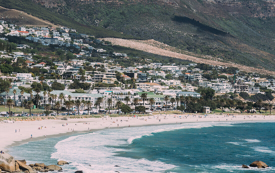 Upmarket Camps Bay lockt mit seinem namensgebenden Strand, der für seinen feinen weißen Sand, das natürliche Felsenschwimmbad und den Blick auf die Zwölf Apostel Berge bekannt ist, viele Menschen an, Kapstadt, Westkap, Südafrika, Afrika