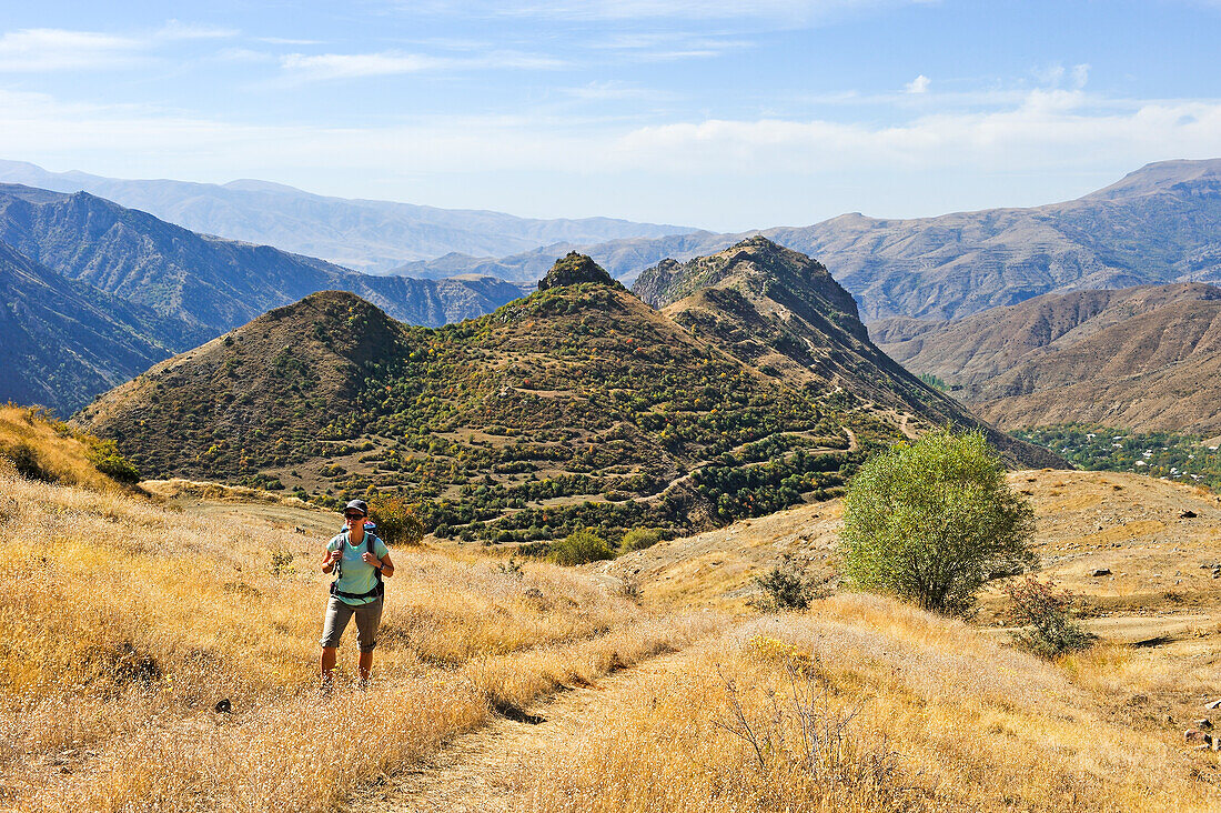 Wanderer auf dem Zugangsweg zum Tsakhats-Kar-Kloster mit der Smbataberd-Festung im Hintergrund, nahe Yeghegnadzor, Provinz Vayots Dzor, Armenien, Eurasien