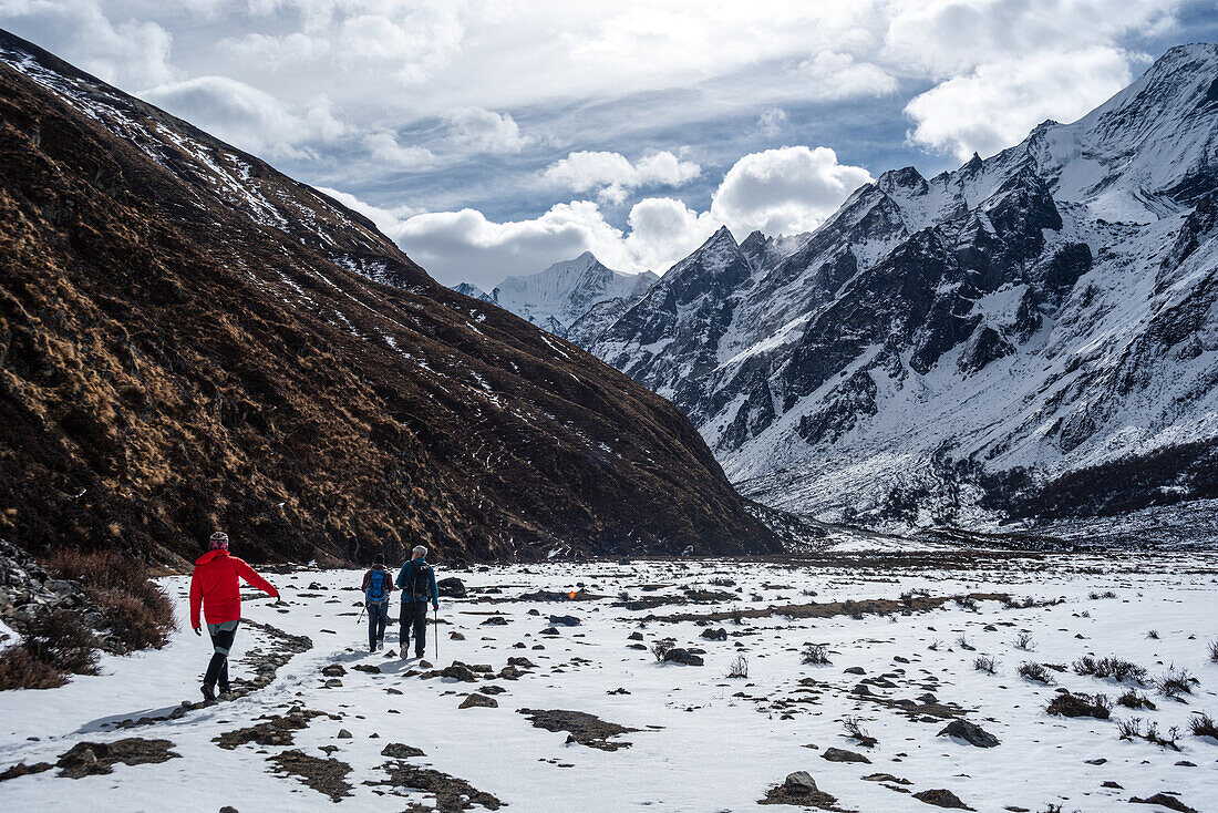 Hikers crossing a snowy area in high altitude winter valley on the Langtang trek in Kyanjin Gompa, Himalayas, Nepal, Asia