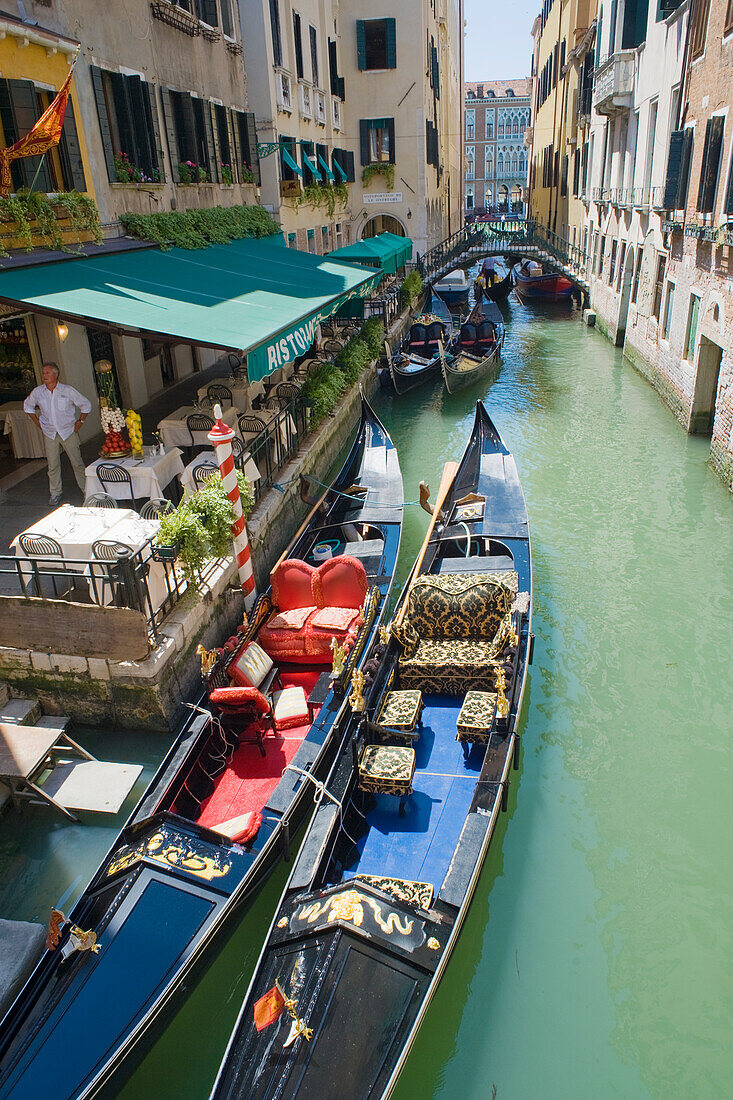 Two elegant gondolas moored in front of a restaurant along a narrow canal leading off the Grand Canal, Venice, UNESCO World Heritage Site, Veneto, Italy, Europe