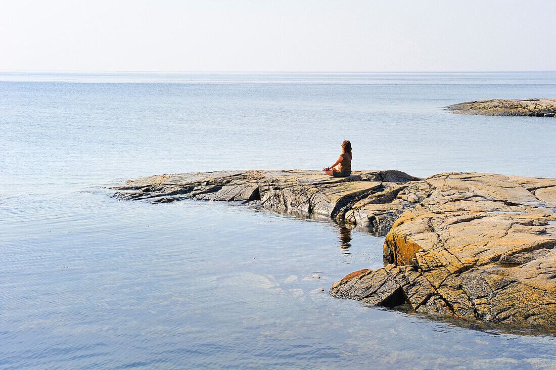 Frau steht auf einem Felsen am Zusammenfluss von Saguenay und Sankt-Lorenz-Strom, Tadoussac, Region Cote-Nord, Provinz Quebec, Kanada, Nordamerika