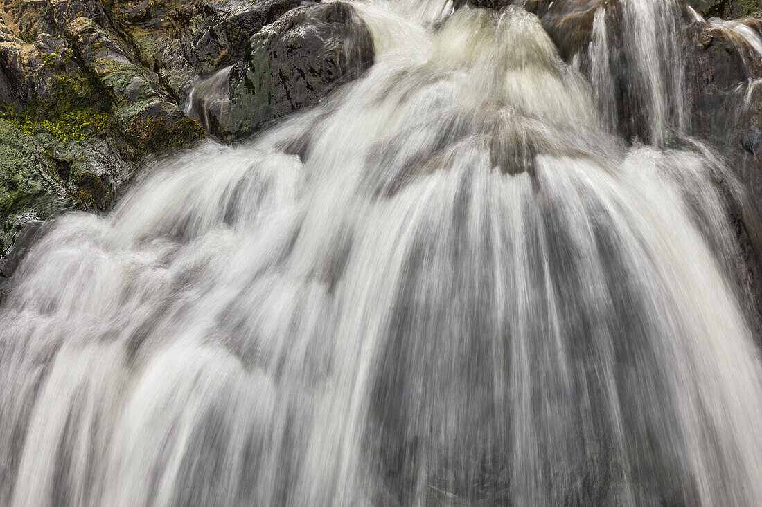 Wasserfall, der sich über eine felsige Klippe ergießt, mit unscharfer Bewegung, resultierend aus einer langen Verschlusszeit; am Welcombe Mouth, Hartland, Nord-Devon, England, Vereinigtes Königreich, Europa