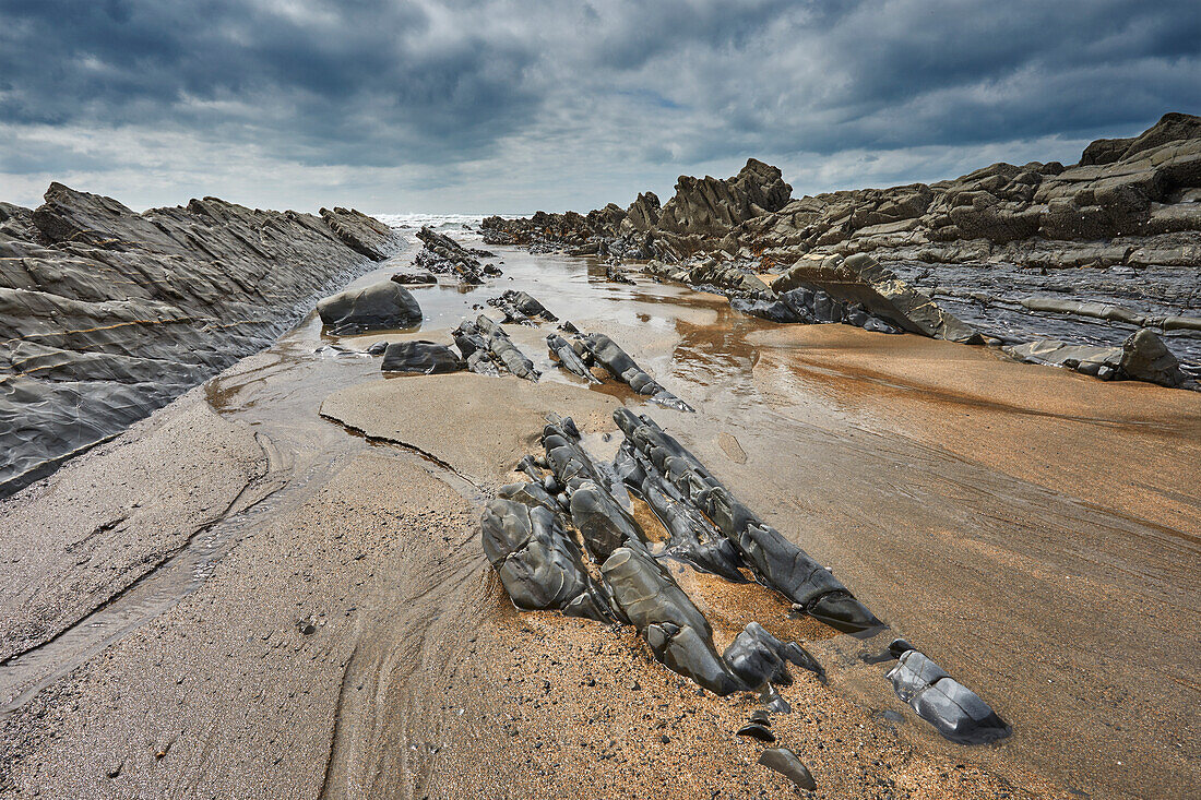 Ein felsiges Ufer bei Ebbe und unter grauem Himmel; an der Welcombe Mouth, Hartland, Nord-Devon, England, Vereinigtes Königreich, Europa