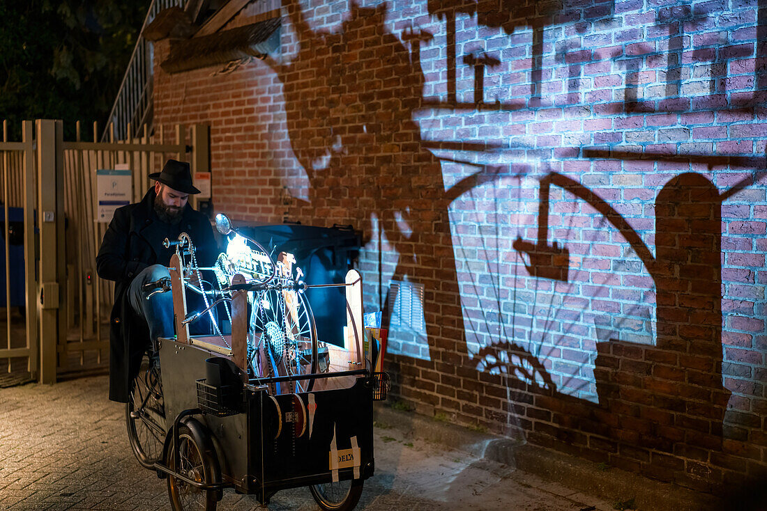 Künstler mit einem Wagen, der während des Glow-Lichtfestivals Schatten auf eine Wand wirft, Eindhoven, Nordbrabant, Niederlande, Europa